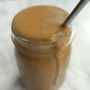 Mason jar with orange spread and a metal spoon inside.